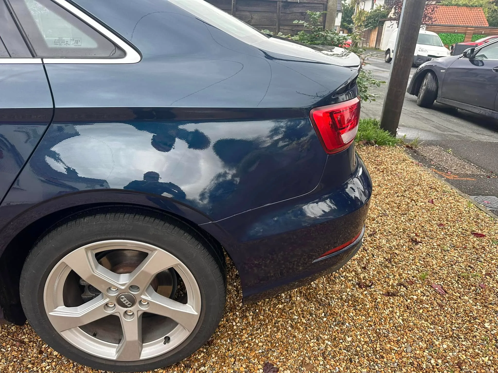 A blue car parked on the side of a road.