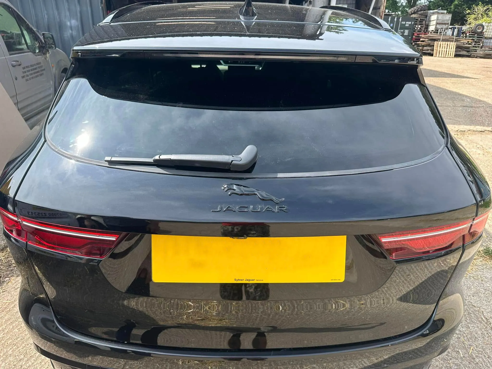 A rear view of a black car with a yellow license plate.