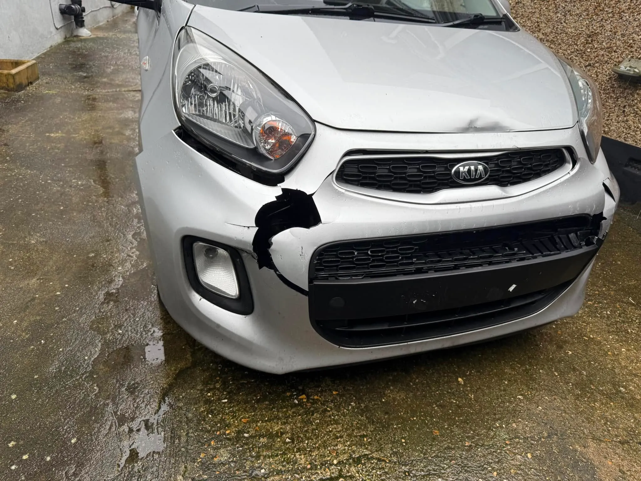 The front of a silver car that has been damaged.